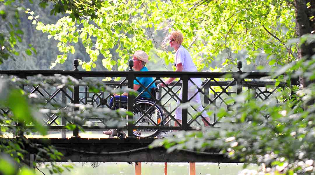 Patient mit Pflegekraft beim Spaziergang im Park