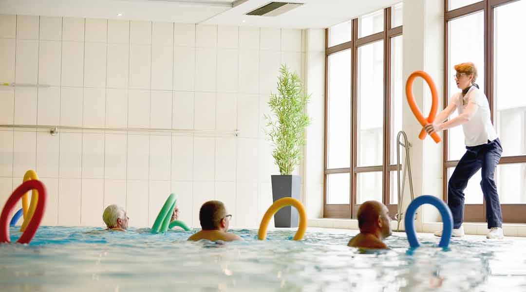 Sporttherapie Trainerin gibt Kurse im Bewegungsbad mit Poolnudel